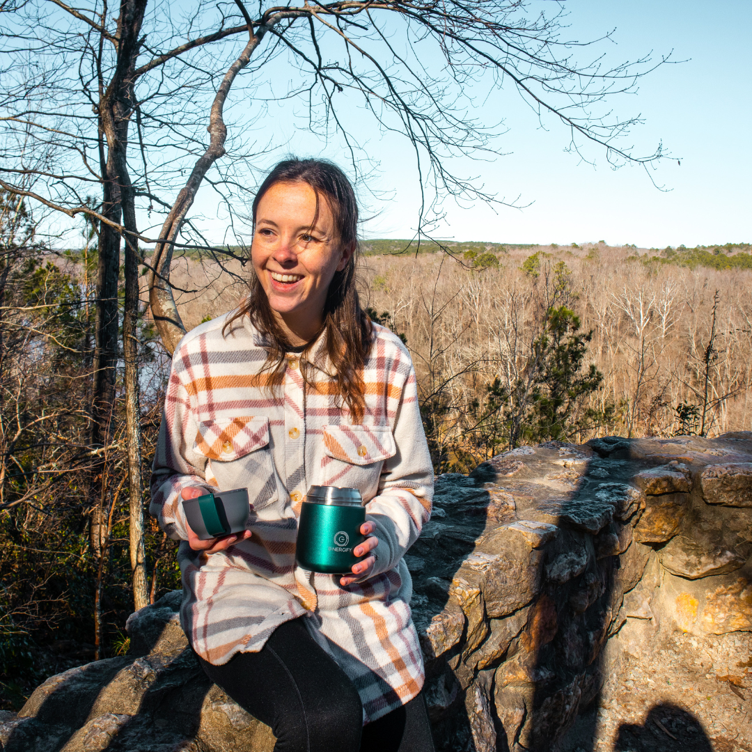 A young woman holding 17 oz Brilliant Green Energify vacuum insulated food jar and smiling. She is outdoors