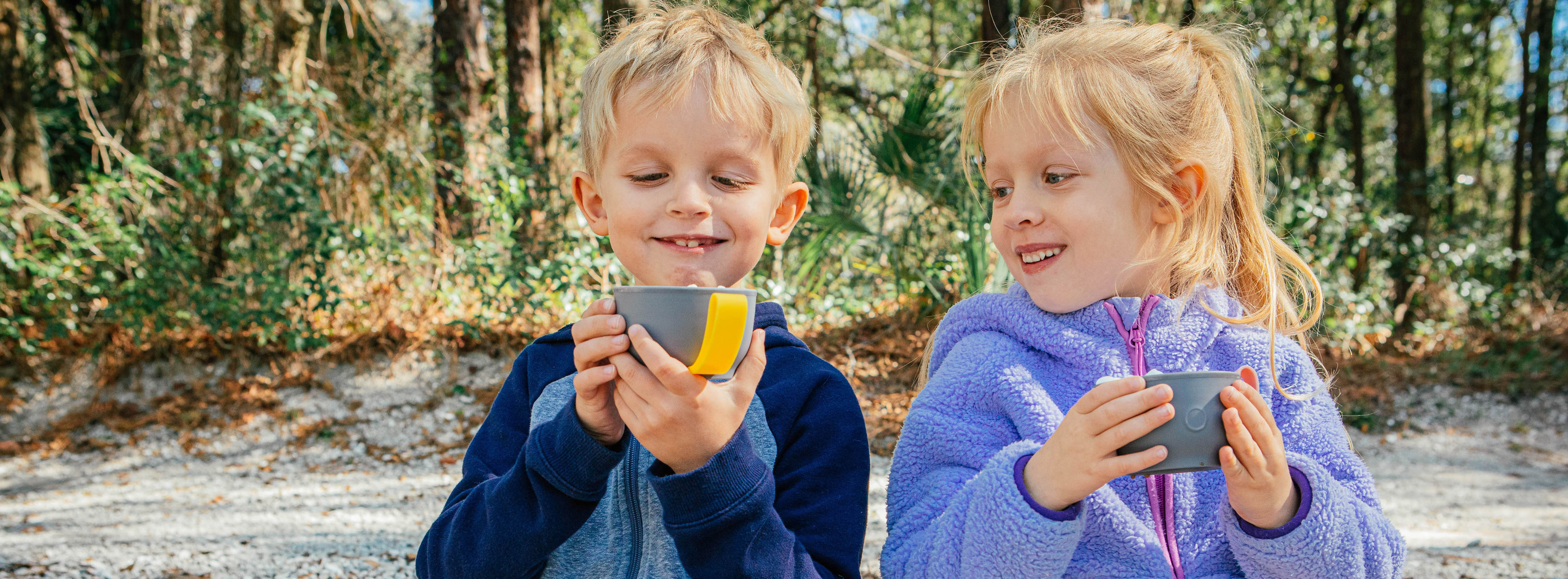 Girl and boy are drinking cocoa from thermos